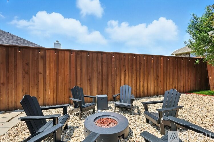 A backyard with a fire pit and chairs.