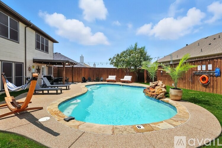 A small residential pool surrounded by a concrete patio and a wooden fence.