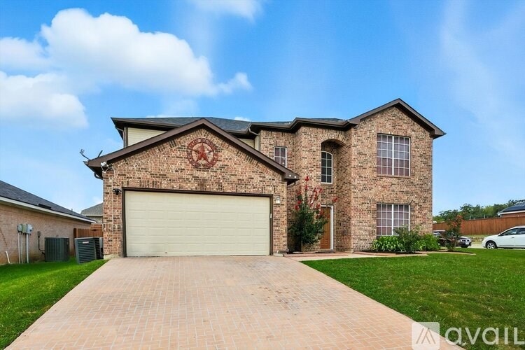 A house with a brick facade and a large driveway in front.