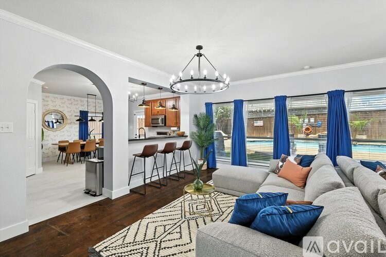 A living room with a grey couch and a chandelier.