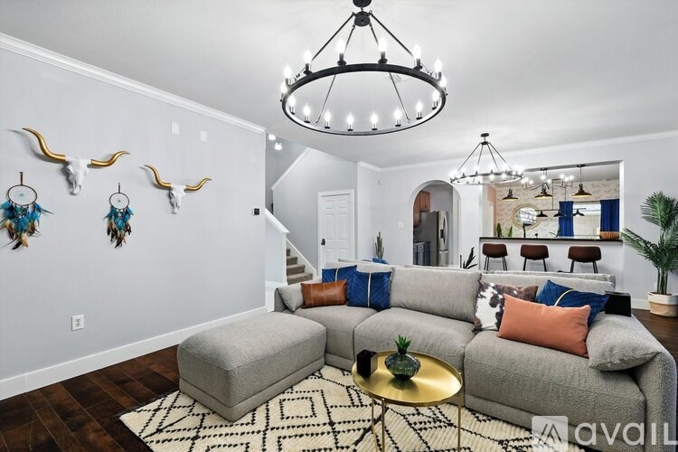 A living room with a grey couch, a coffee table, and a chandelier.