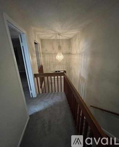 A hallway with a wooden railing and a light hanging from the ceiling.