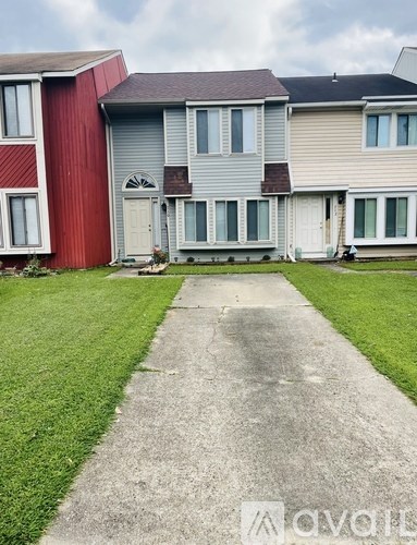 A red building with a grey door and windows is next to a green lawn.