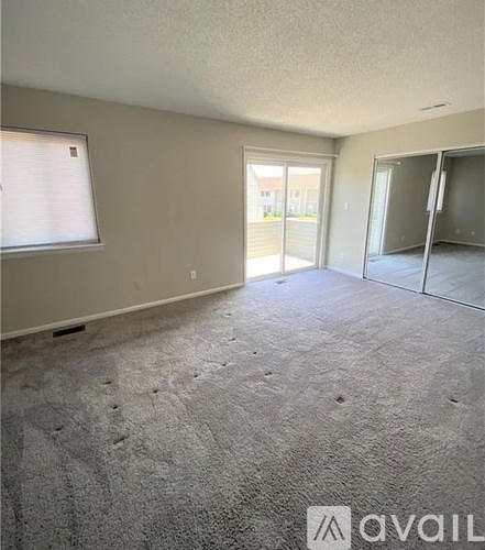 A carpeted room with a window and sliding glass doors.
