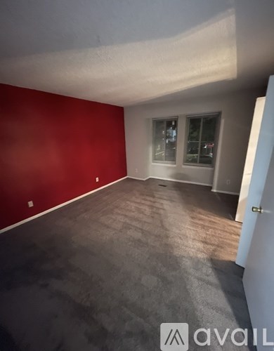 A room with a red wall and a carpeted floor.