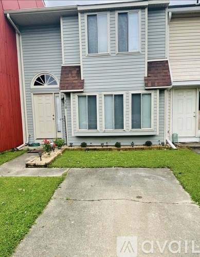A grey house with a red door and a small garden in front.