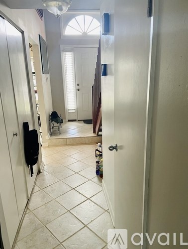 A hallway with a white door and a black coat hanging on it.