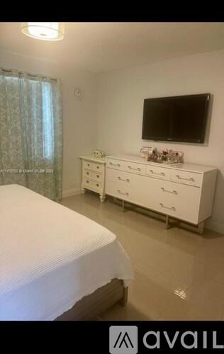 A bedroom with a bed, dresser, and television.