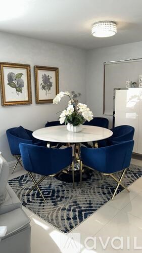 A round table with a vase of flowers on it and four chairs around it.