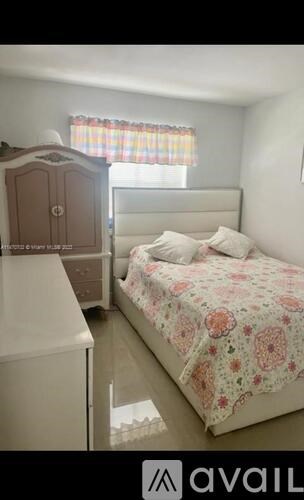 A bedroom with a bed, a wardrobe, and a window with a curtain.