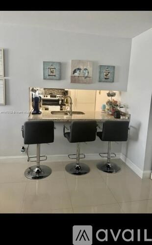 A kitchen with black chairs and a white wall.