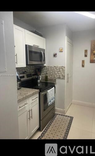 A kitchen with a black countertop and white cabinets.