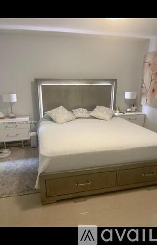 A bedroom with a large bed and a nightstand with a lamp.