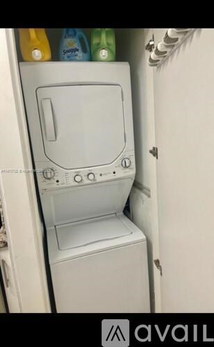 A white washing machine is in a cabinet with a door open.