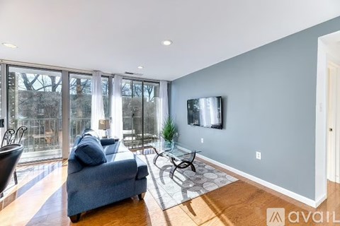 A living room with a blue couch and a television on the wall.