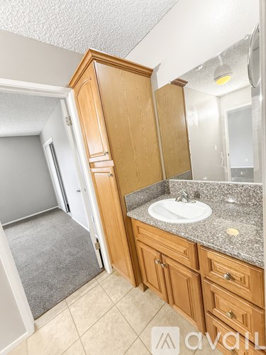 A bathroom with a sink and wooden cabinets.
