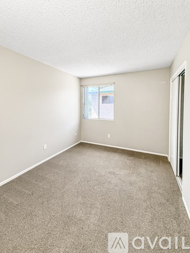 A room with a carpeted floor and a window with blinds.