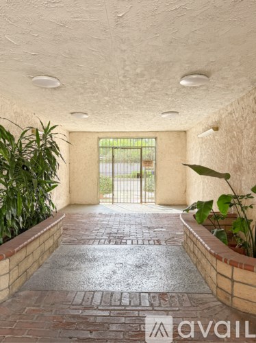 A hallway with a brick floor and a metal gate in the background.