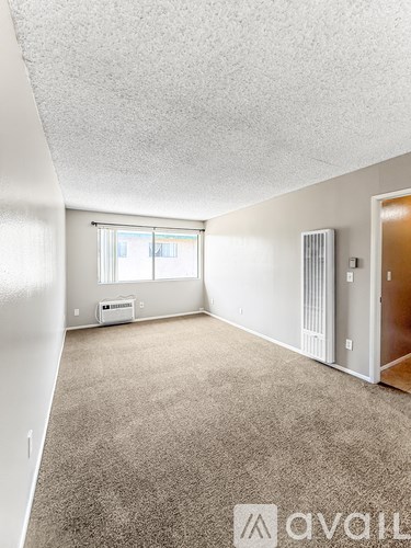 A room with a carpeted floor and a window with blinds.