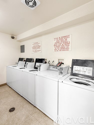 A laundry room with washers and dryers and a sign on the wall.