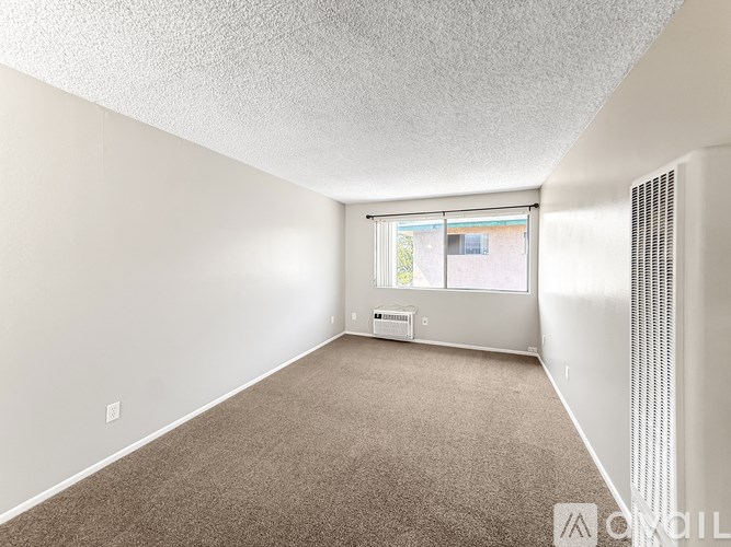 A room with a carpeted floor and a window with blinds.