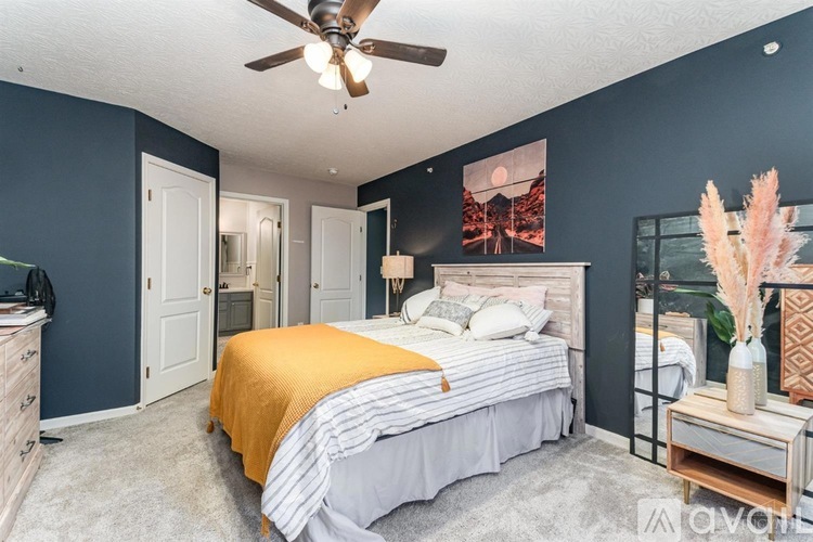 A bedroom with a bed, dresser, and ceiling fan.