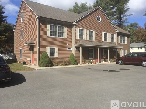 A two-story brick house with a red door and a car parked in front.
