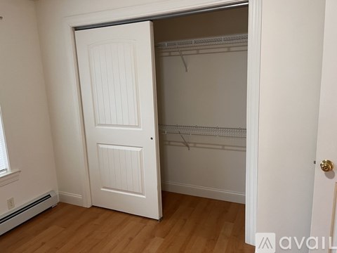 A bedroom with a bed, a window with curtains, and two doors.