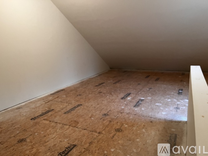 A room under construction with wooden flooring and white walls.