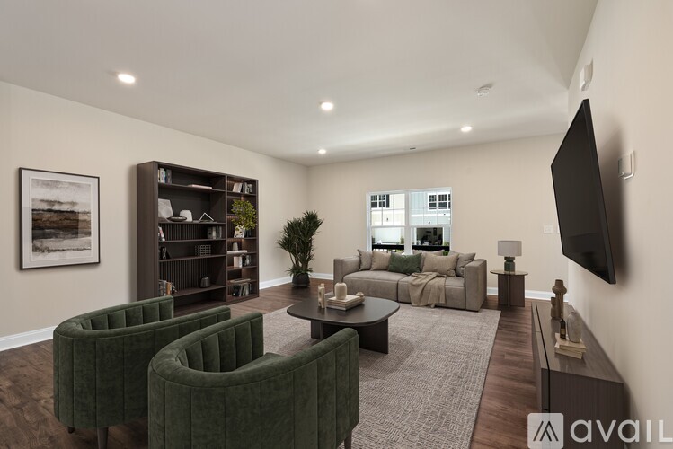 A living room with a green velvet armchair, a black flat screen TV, and a coffee table.