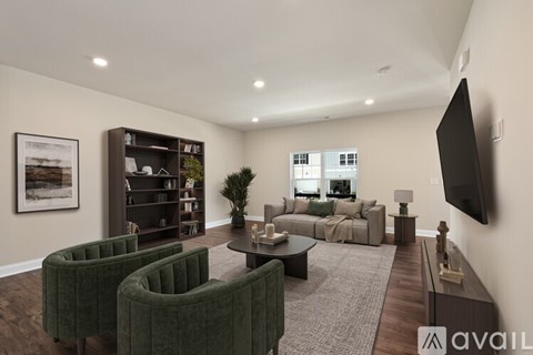 A living room with a green velvet armchair, a black flat screen TV, and a coffee table.