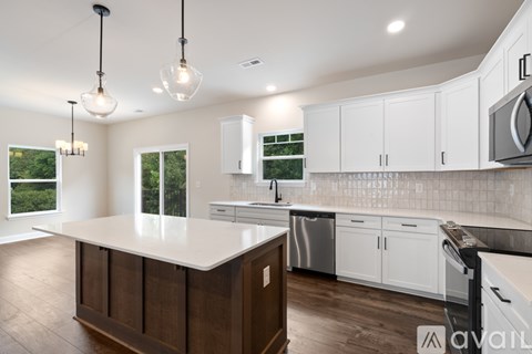A kitchen with white cabinets and a wooden island.