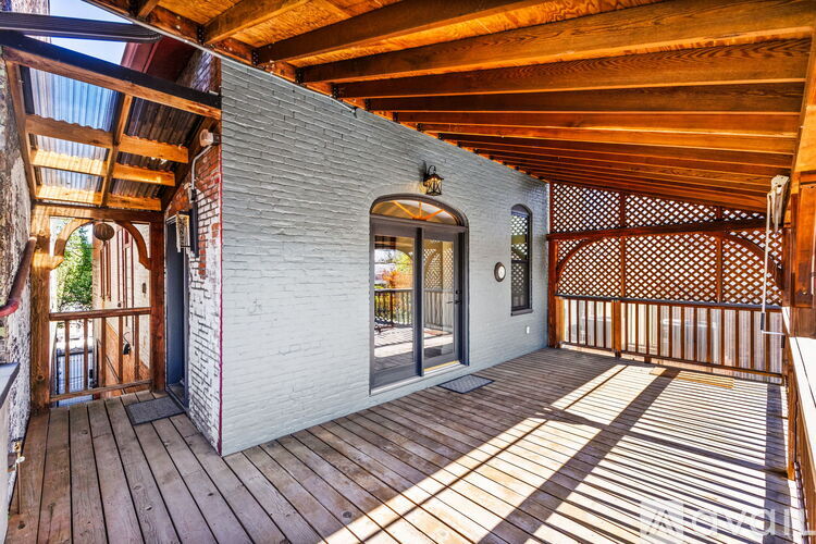 A wooden deck with a white brick building in the background.