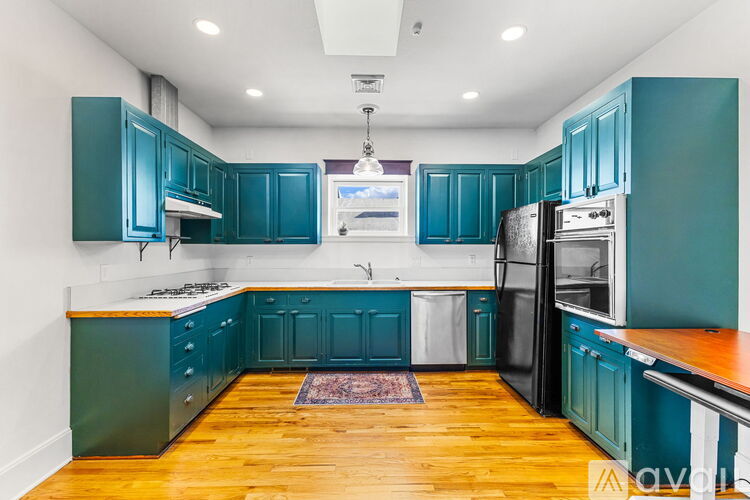 A kitchen with teal cabinets and a black refrigerator.