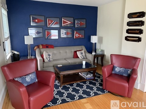 A living room with a grey couch, two red chairs and a coffee table.