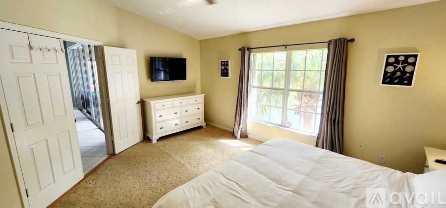 A bedroom with a large bed, a dresser, and a flat-screen TV.