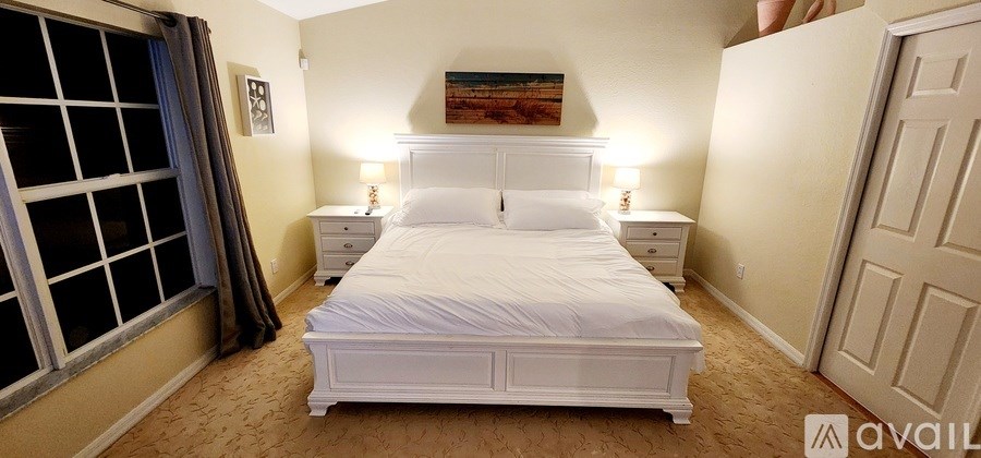 A bedroom with a large bed and a painting on the wall.