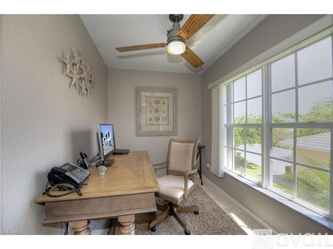 A room with a desk, chair, and a ceiling fan.
