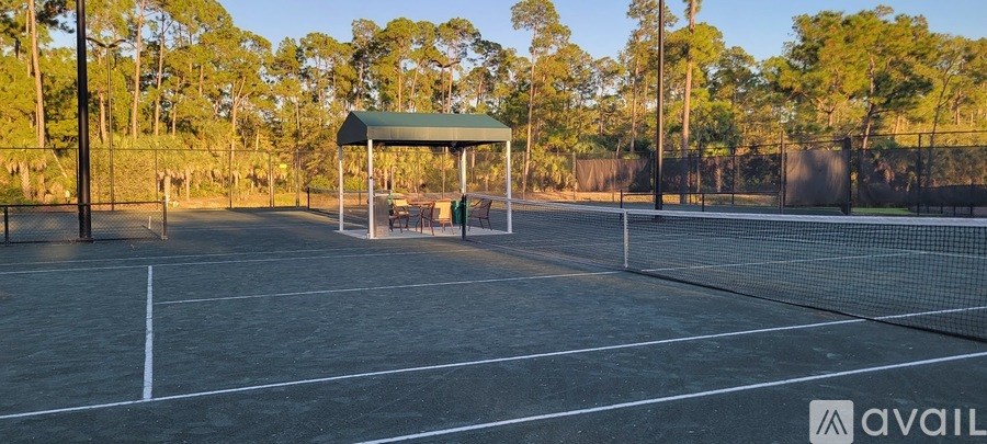 A serene lake surrounded by trees and grass under a clear blue sky.
