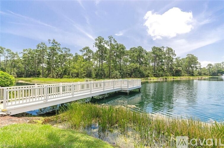 A wooden bridge over a calm lake with greenery in the background.