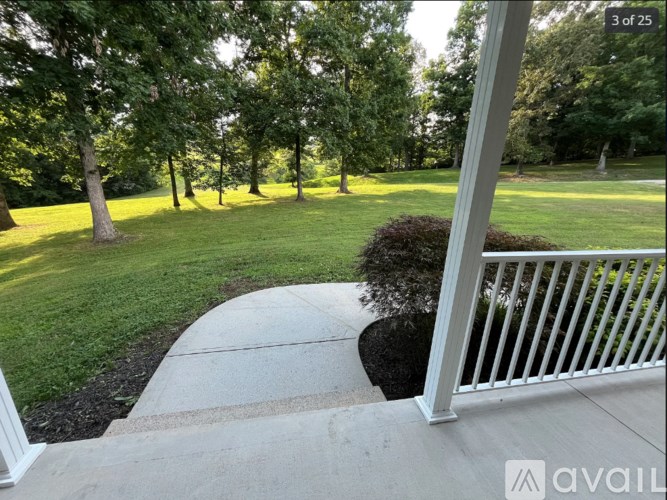 A white railing on a concrete walkway leads to a lush green lawn.