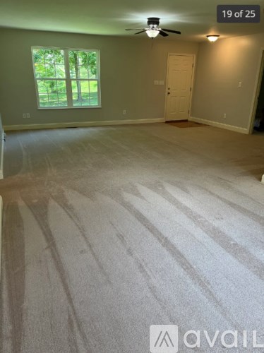 A room with a carpeted floor and a ceiling fan.