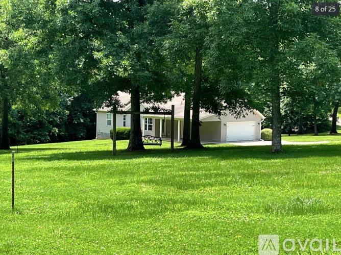 A white house is surrounded by trees in a grassy area.