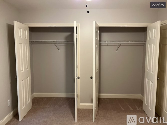 Two white closet doors with hangers on the shelves.