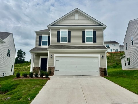 A two-story house with a garage door and a driveway.