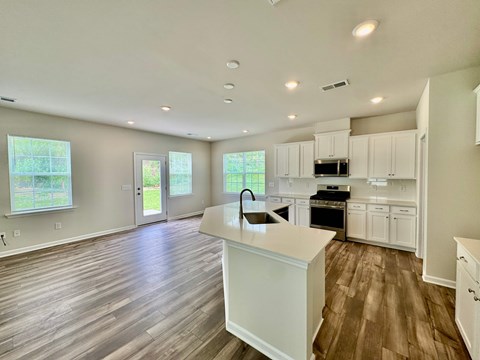 A kitchen with white cabinets and a wooden floor.