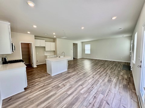 A spacious room with wooden flooring and white cabinetry.