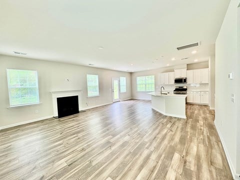 A spacious living room with a fireplace and hardwood floors.