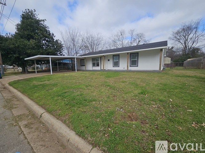 A house with a white exterior and a grey roof is surrounded by a grassy area.