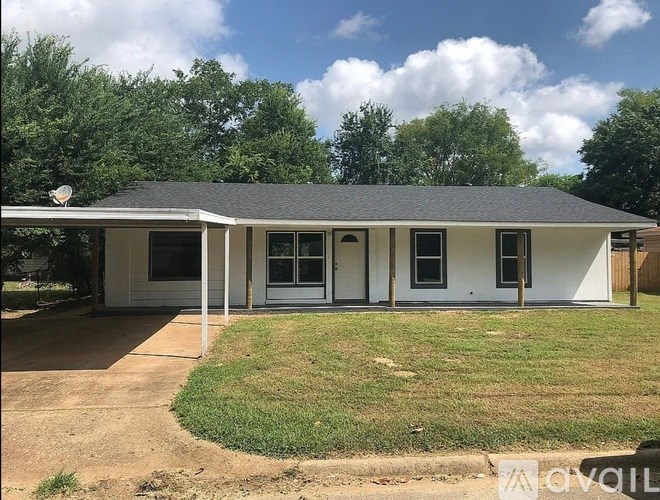 A white house with a grey roof and a green lawn in front.